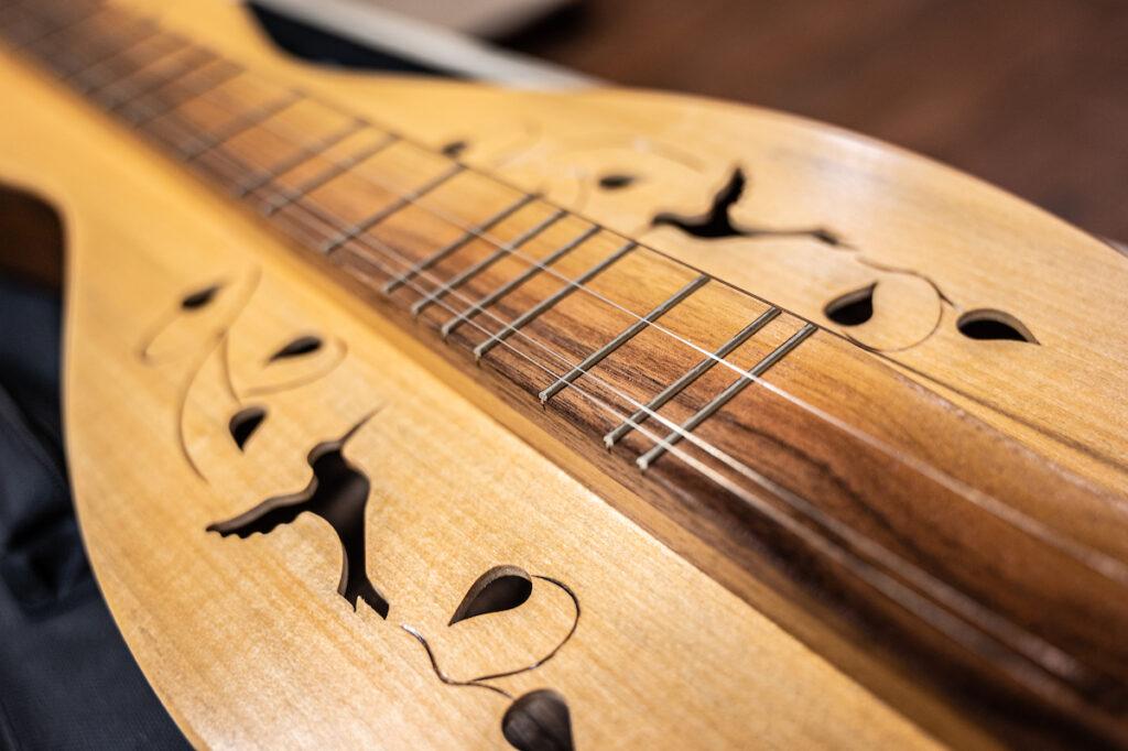 Close up of a dulcimer with hummingbirds engraved in it