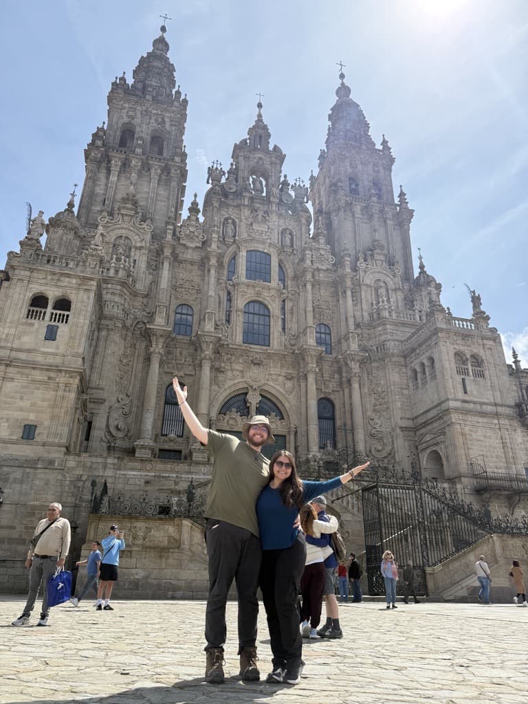 Two students posing in front of the Santiago de Compostela Cathedral in Spain on a sunny, spring day.